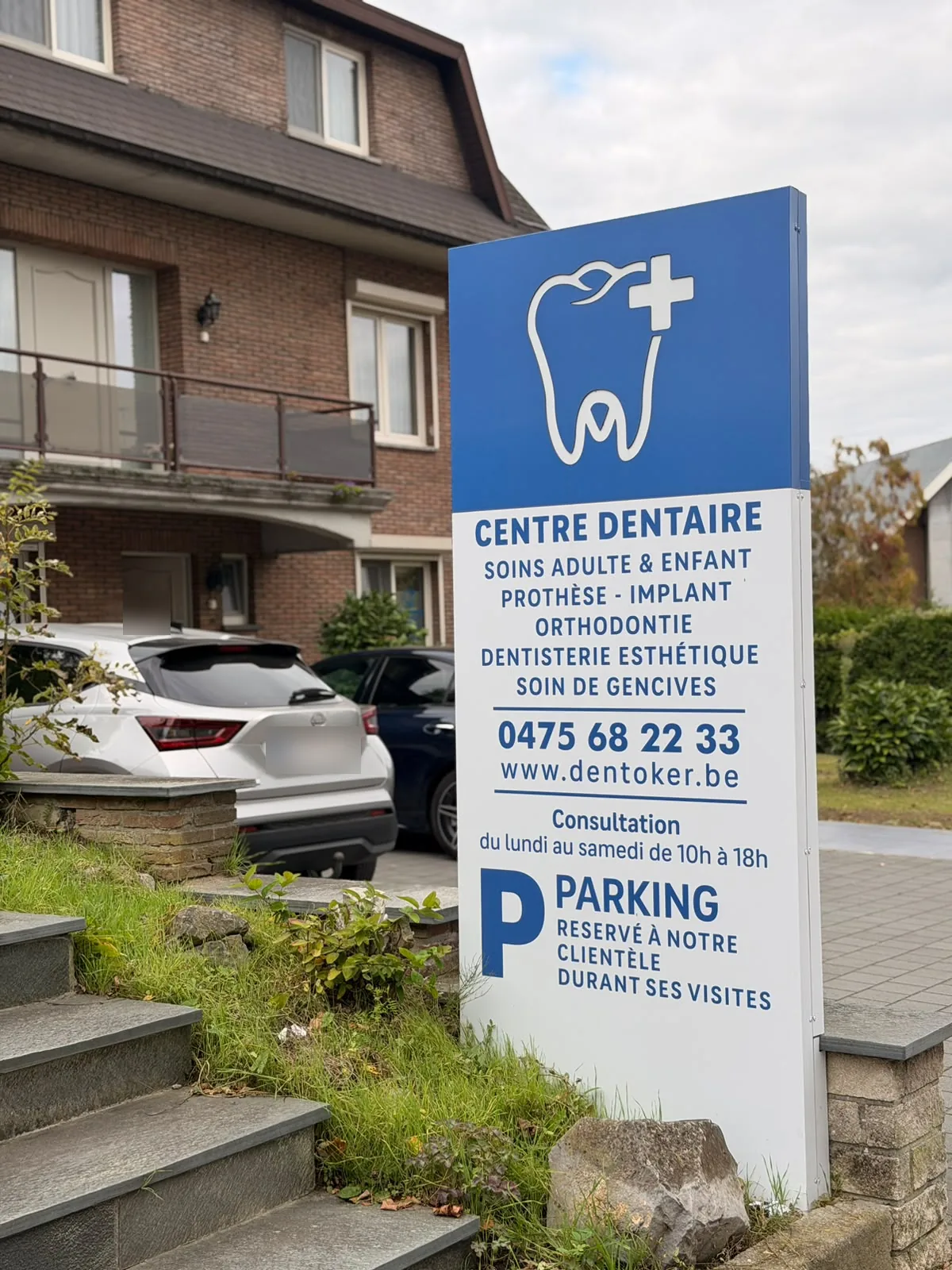 Le panneau du centre dentaire Dentoker, avenue Mutsaard 88, et le parking réservé aux patients devant le cabinet